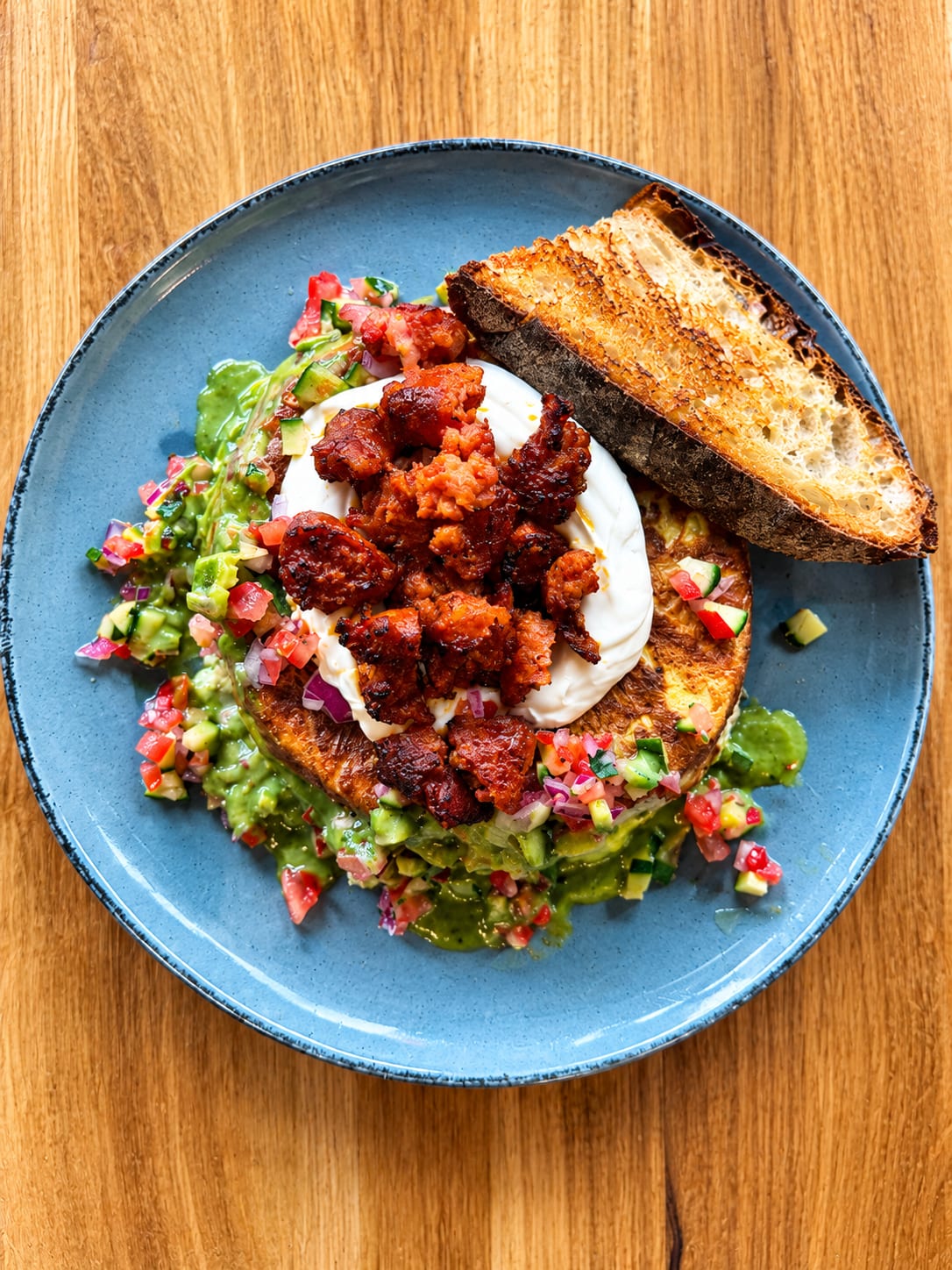 Avocado, Sauerteigbrot und würziges Topping auf blauem Teller — Brunch by Sole, Berlin-Schöneberg